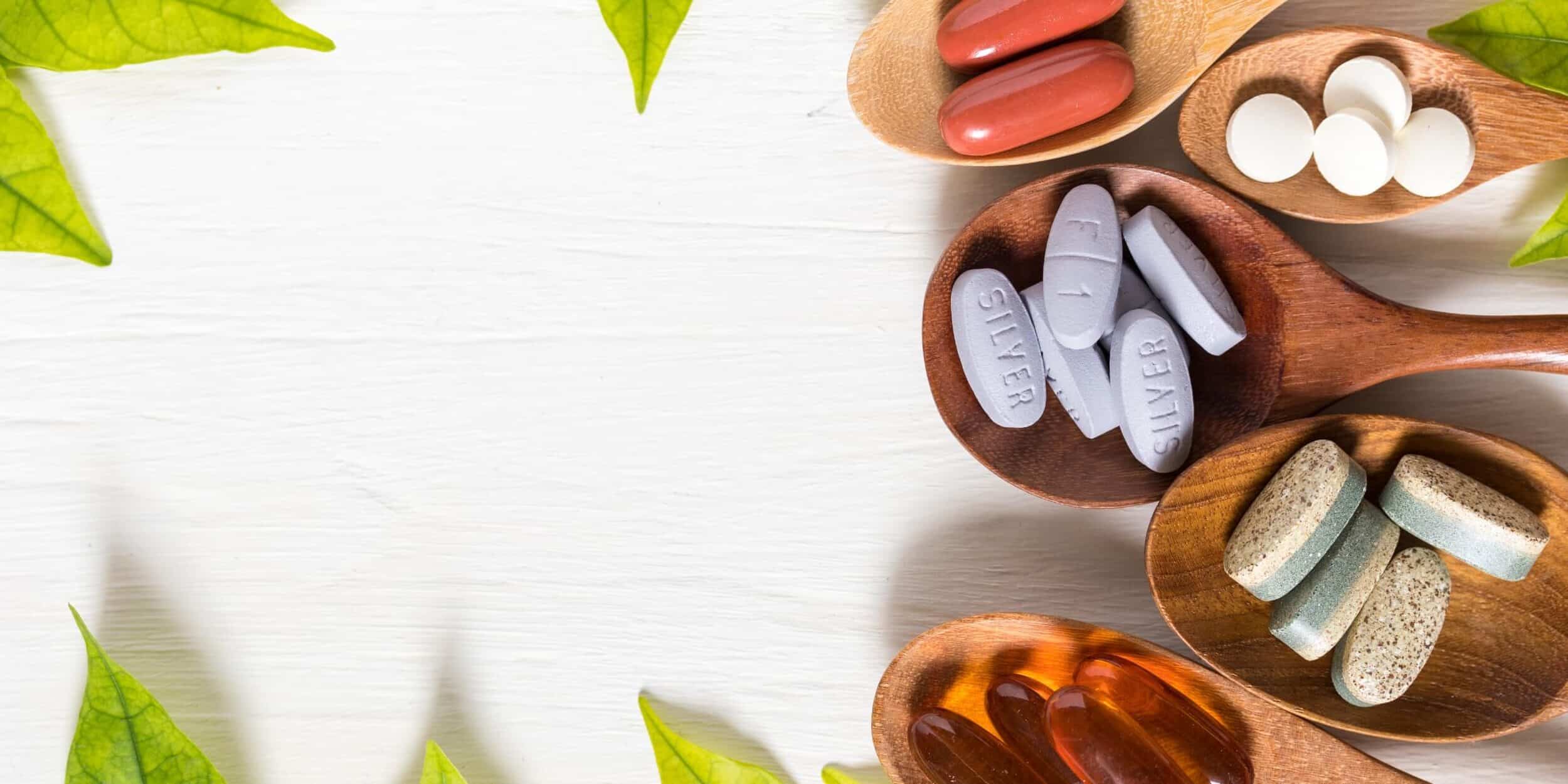 variety-vitamin-pills-wooden-spoon-white-background-with-green-leaf